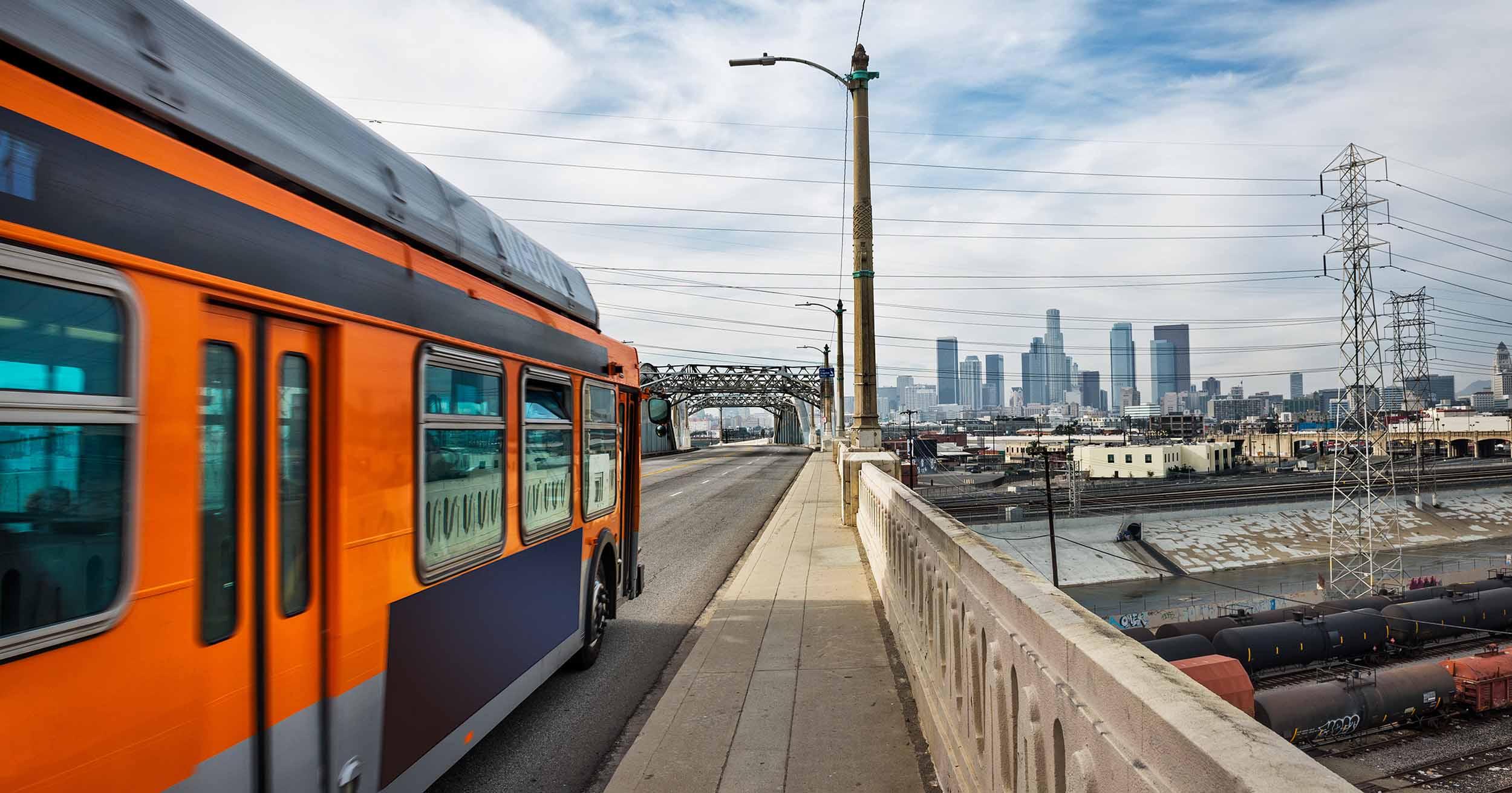 An LA Metro bus driving across a bridge towards the city.